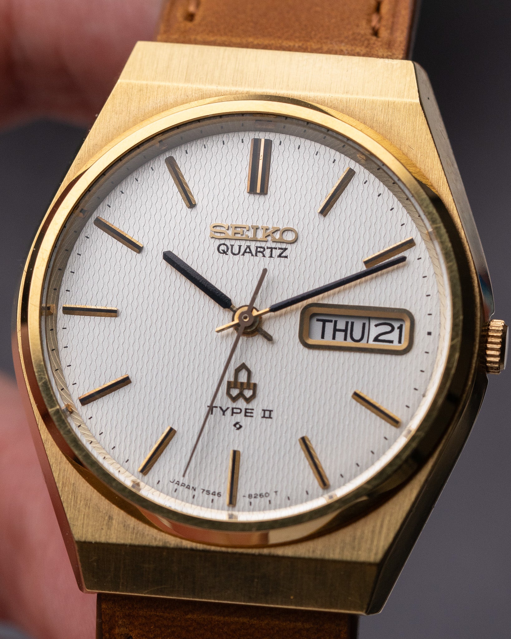 Gold Seiko watch with white face and brown leather strap