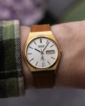 Gold Seiko watch on a wrist with a blurred background