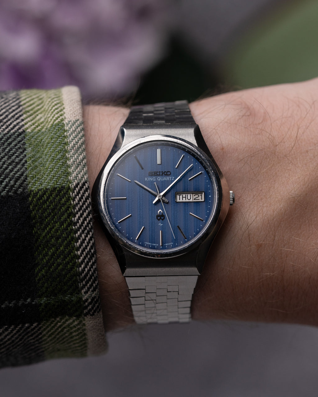 Close-up of a person wearing a Seiko watch with a blue face on a blurred background